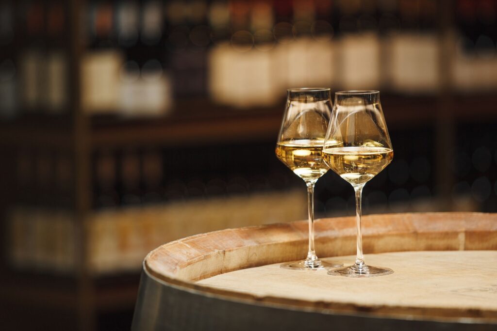 Two glasses of white wine on a barrel in a wine cellar