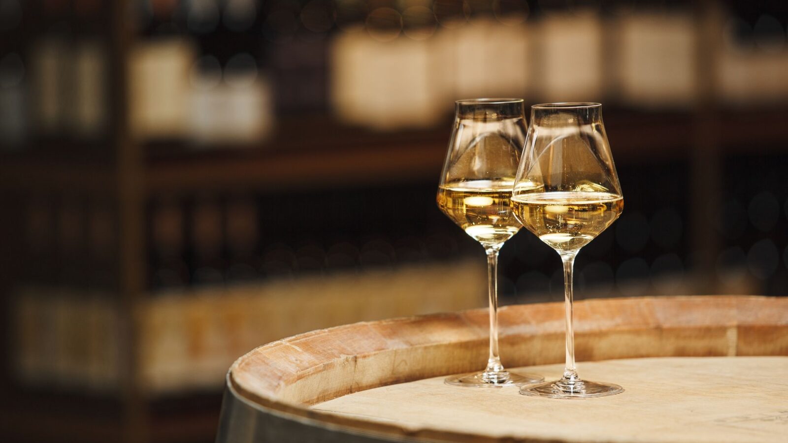 Two glasses of white wine on a barrel in a wine cellar