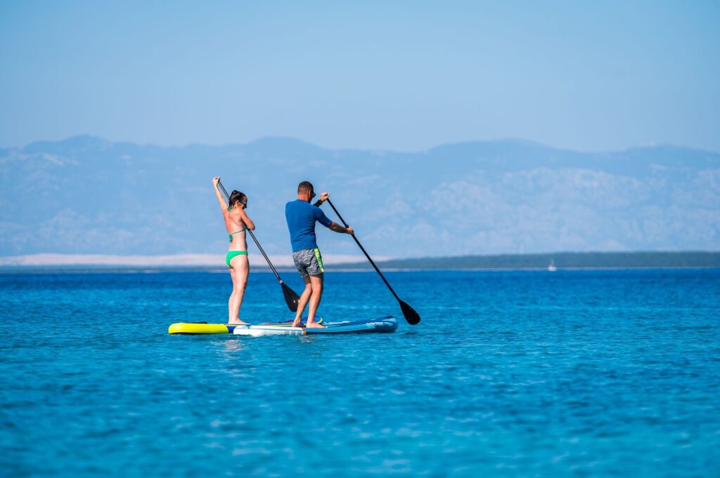 Couple stand-up paddleboarding at sea