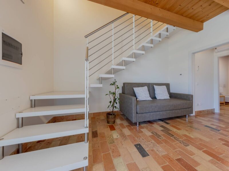 Soggiorno con divano letto e scala al primo piano